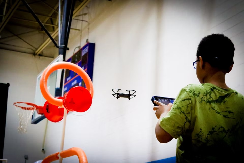 Young participant piloting a drone through a hoop